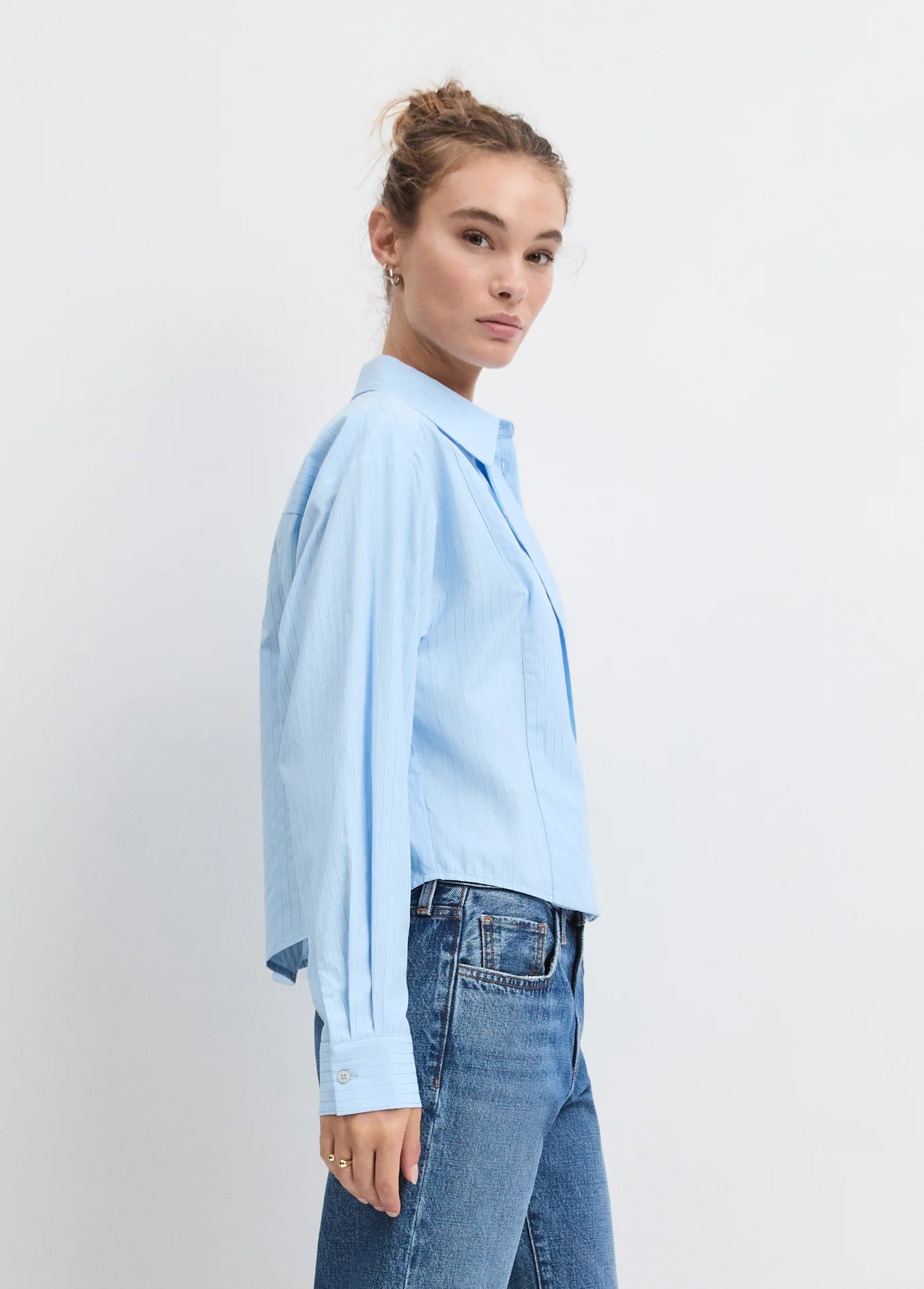 Model wearing the light blue stripe jenni top with jeans on a white background, side