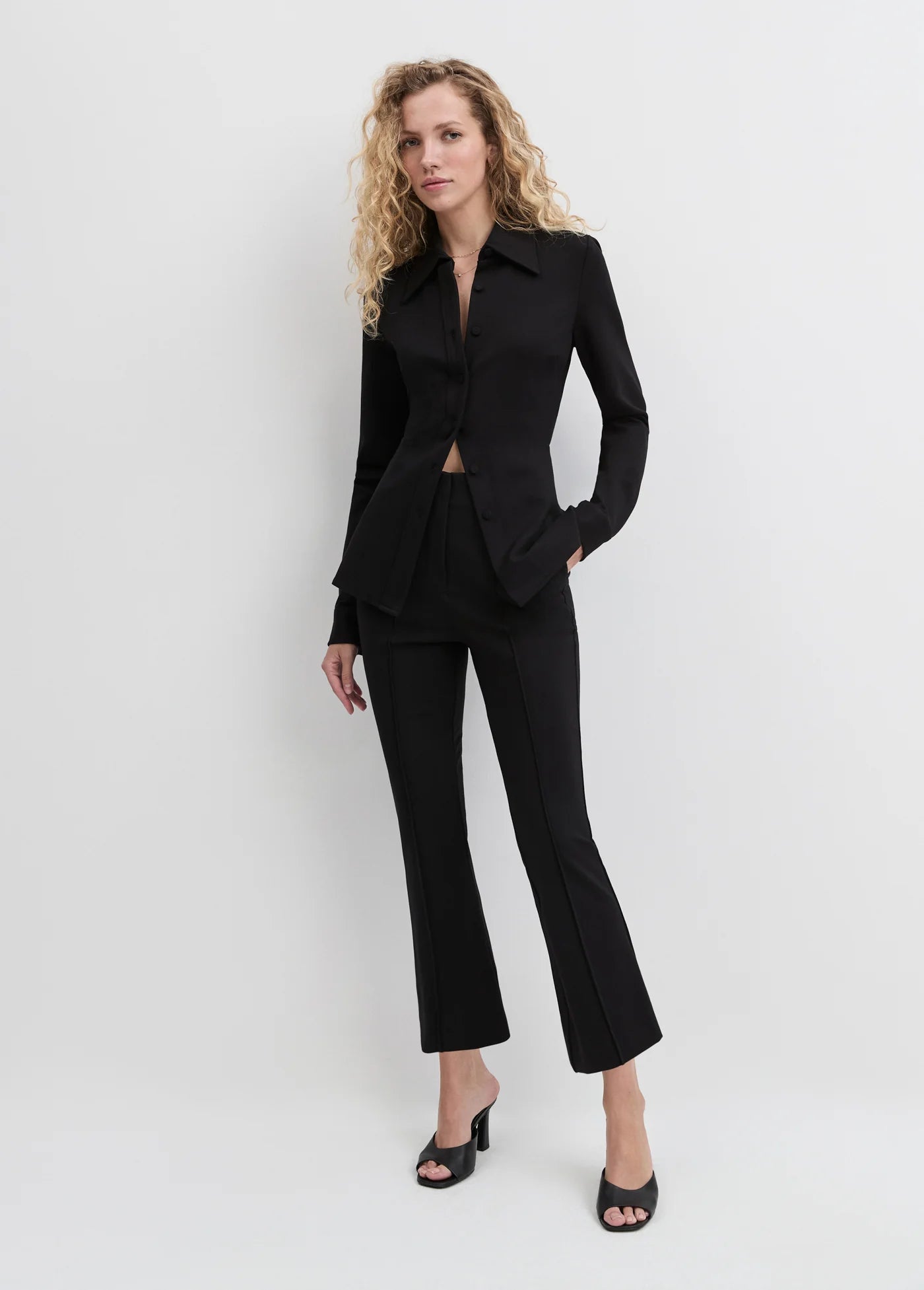 Woman wearing a black suit standing against a white background