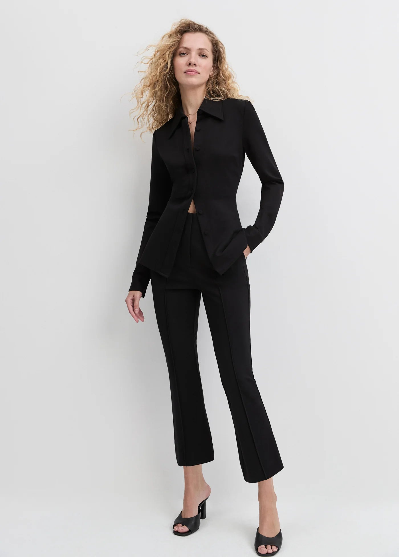 Woman wearing a black suit against a white background