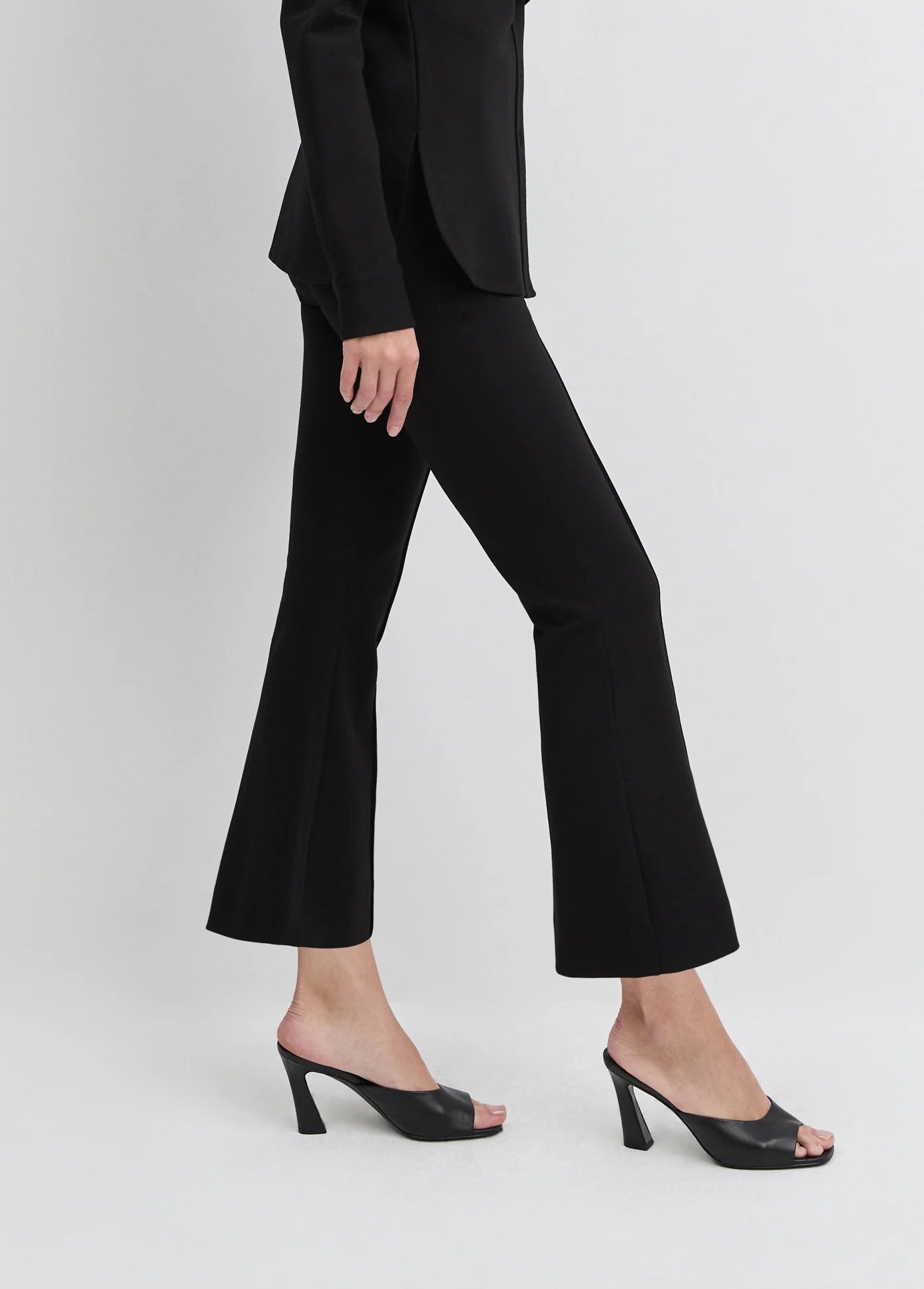 Person wearing a black suit with flared pants on a white background