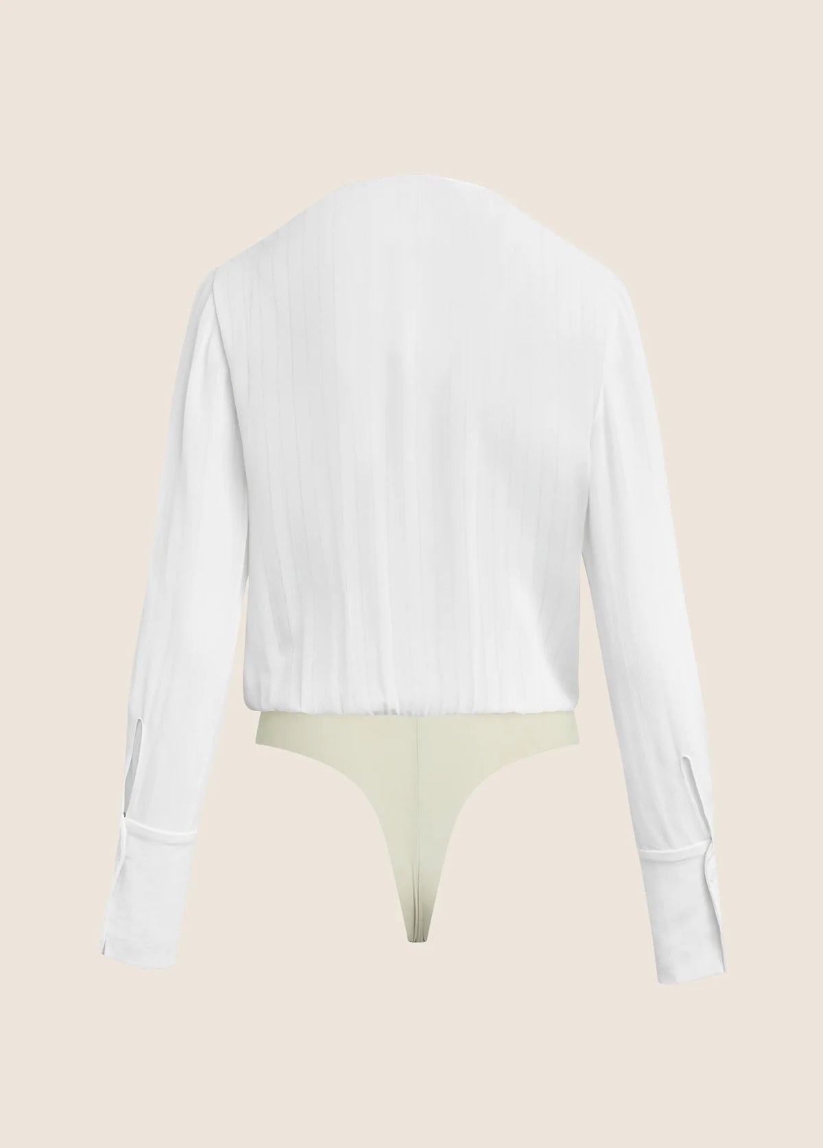 A white long-sleeve cropped shirt shown from the back, layered over a pale yellow-green thong, against a solid light beige background.