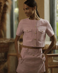 Woman wearing a pink outfit with gold buttons in an indoor setting