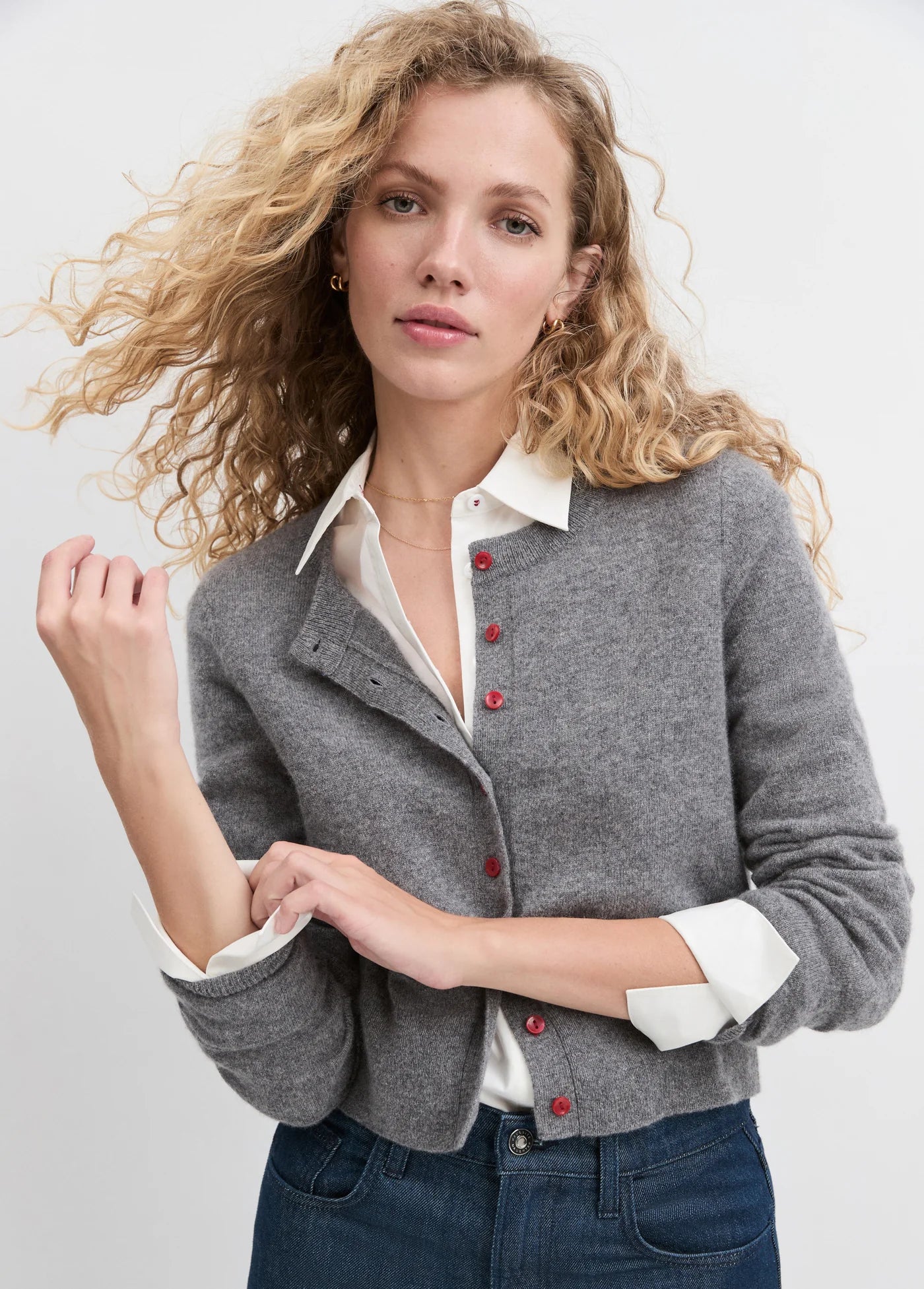 Woman wearing a gray cardigan with red buttons on a white background