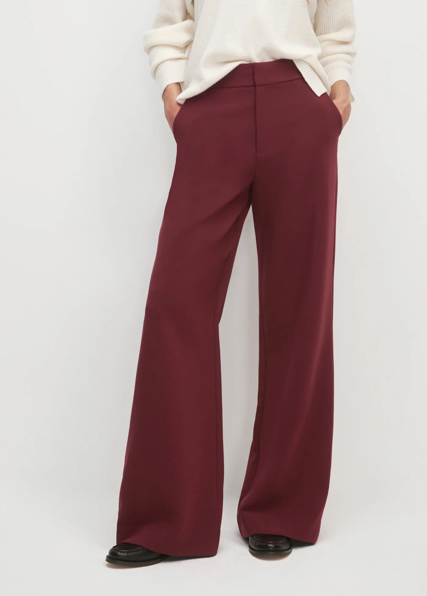Maroon wide-leg pants worn with a white sweater on a light gray background