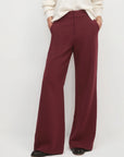 Maroon wide-leg pants worn with a white sweater on a light gray background