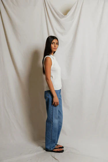 model wearing a white collared shirt with jeans on a white background, side view