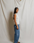 model wearing a white collared shirt with jeans on a white background, side view