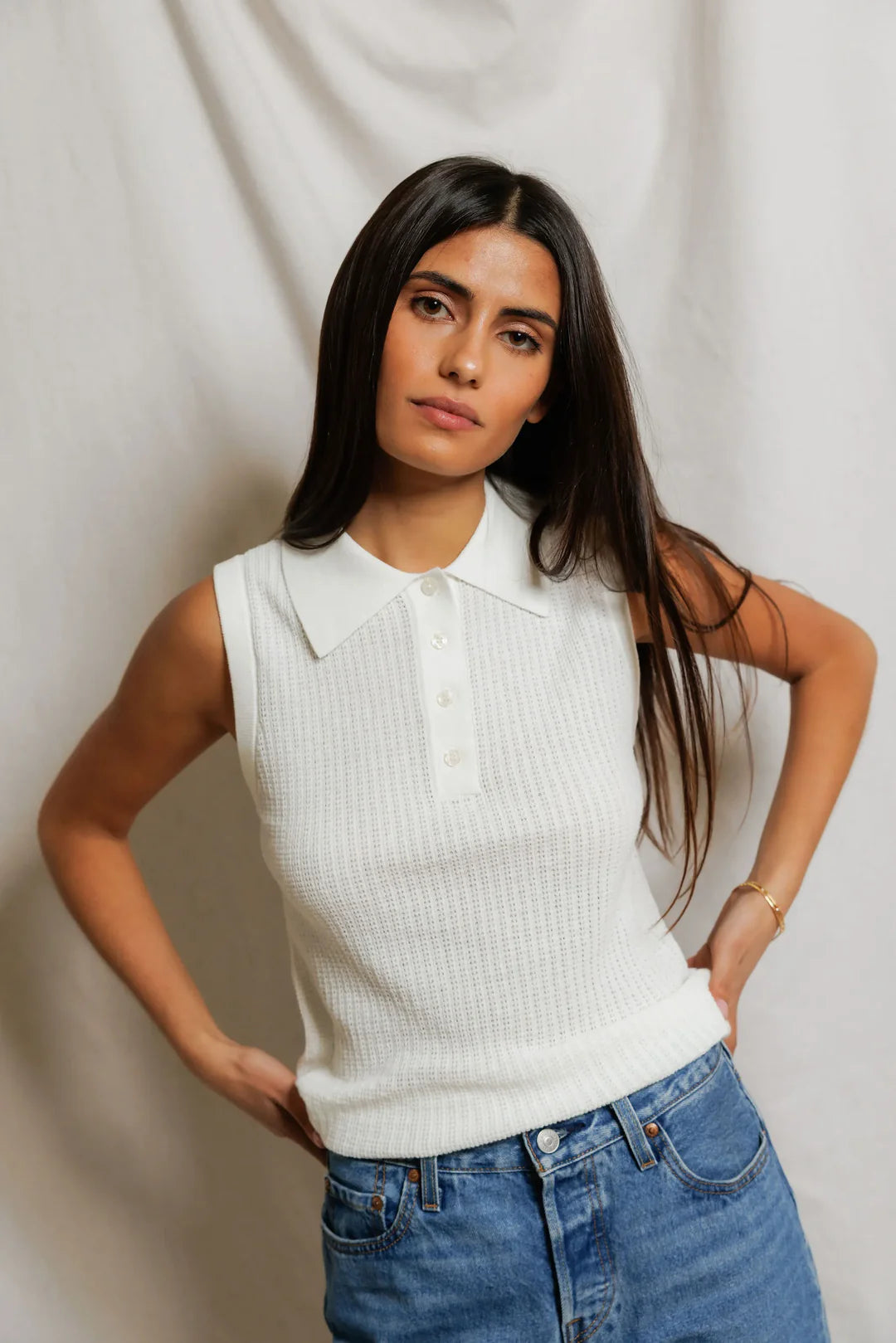 model wearing a white collared shirt with jeans on a white background