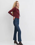 Woman wearing a burgundy sweater and blue jeans against a white background