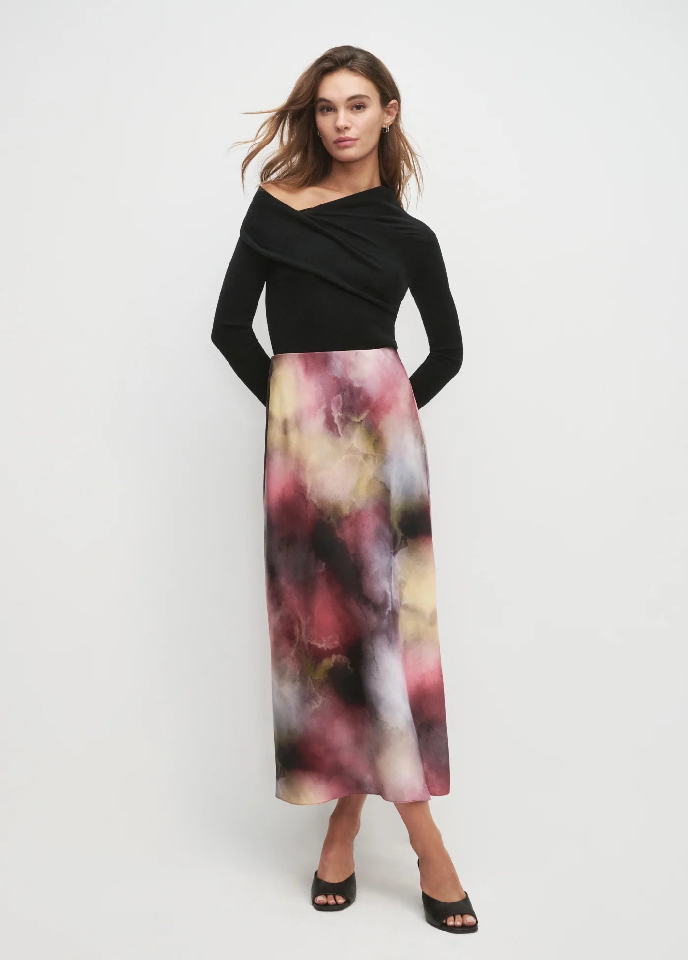 Woman wearing a black top and colorful skirt on a white background