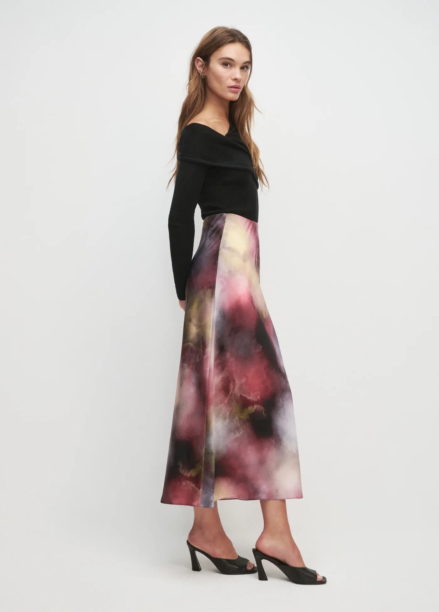 Woman wearing a black top and colorful skirt on a white background