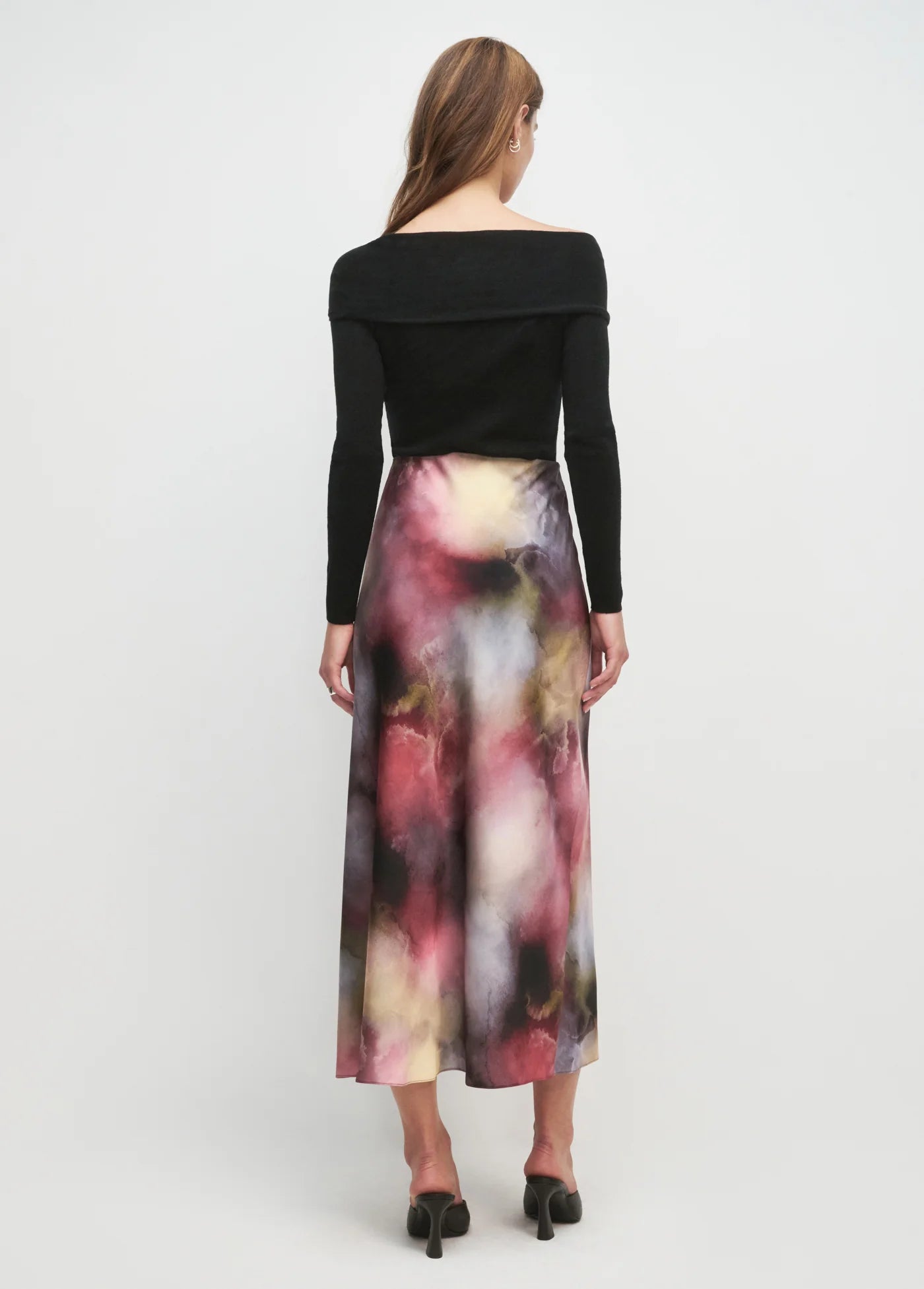 Woman wearing a black top and colorful skirt on a white background