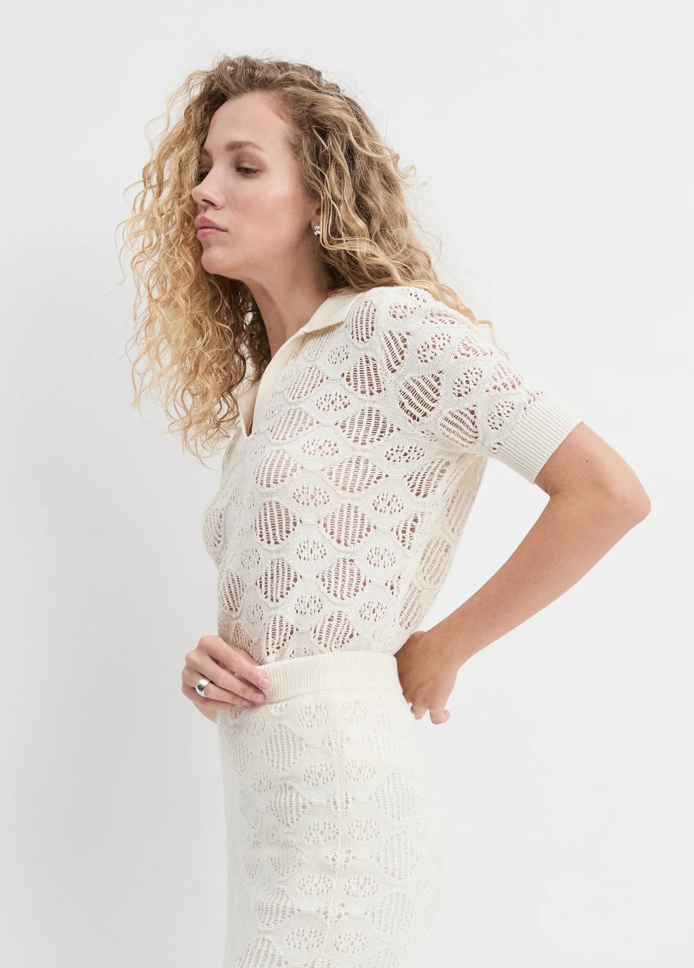 Woman wearing a white lace outfit against a plain background