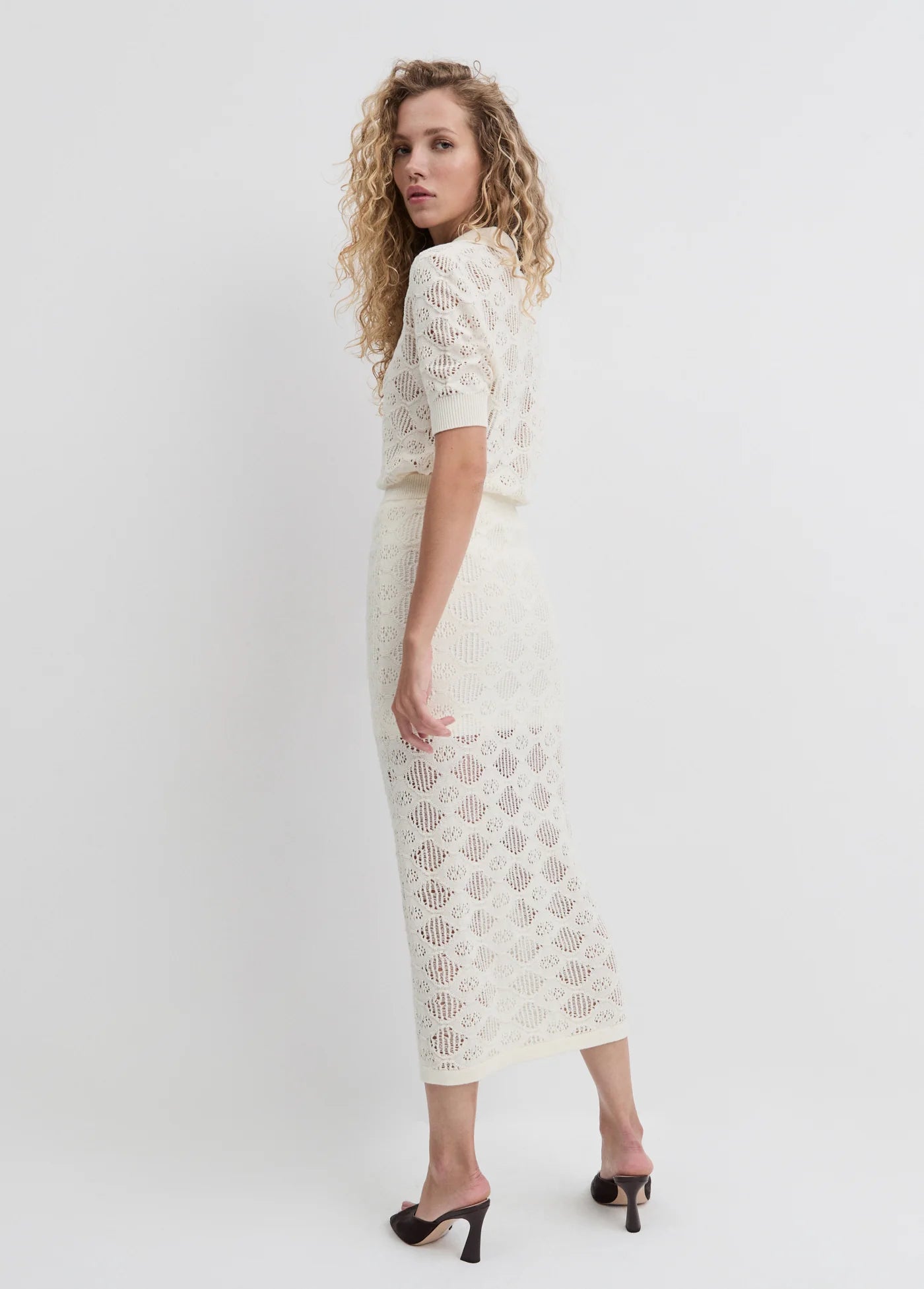 Woman wearing a white lace dress against a white background