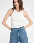 Woman wearing a white tank top and blue jeans on a white background