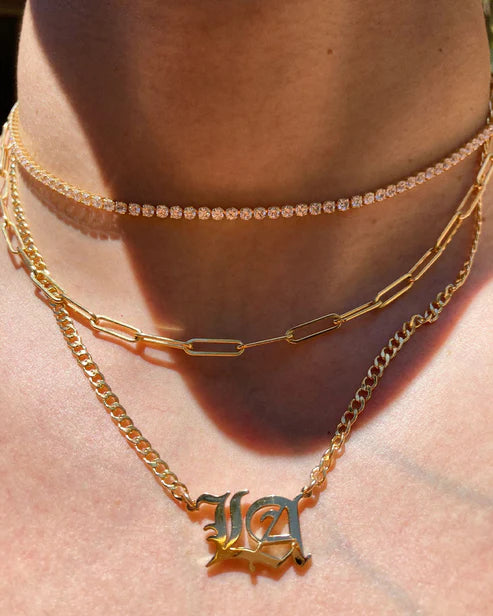 Close-up of layered gold necklaces on a person's neck