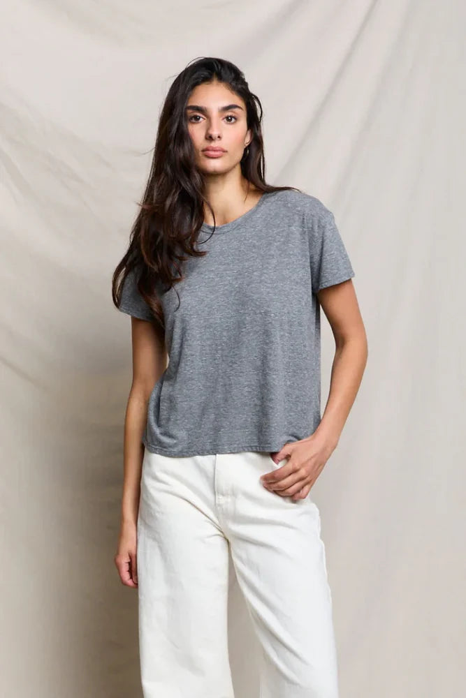 Woman wearing a gray t-shirt and white pants against a beige background