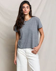 Woman wearing a gray t-shirt and white pants against a beige background
