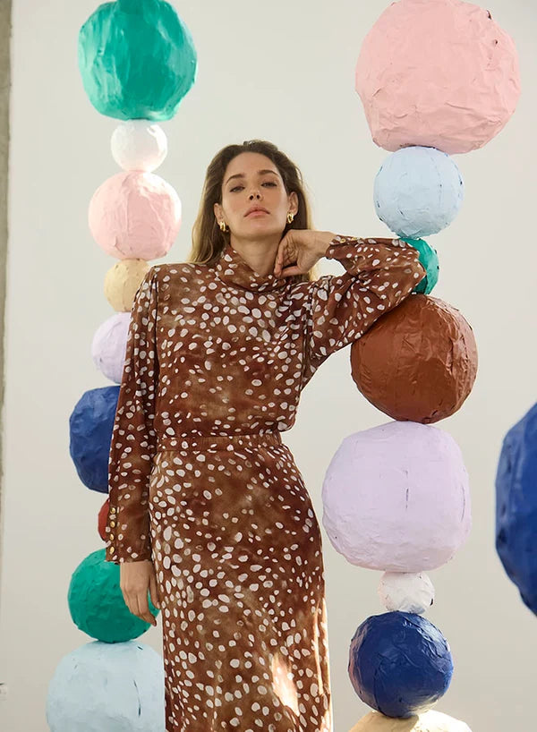 model wearing dapple doe printed top and skirt with art paper mache balls in the background