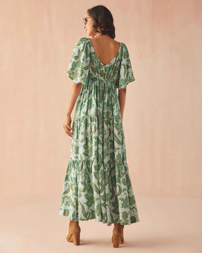 Woman wearing a green patterned dress against a beige background