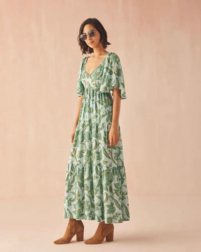 Woman wearing a green patterned dress against a beige background