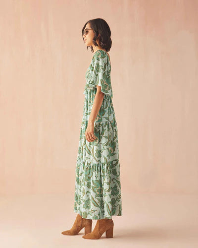 Woman wearing a green patterned dress against a beige background
