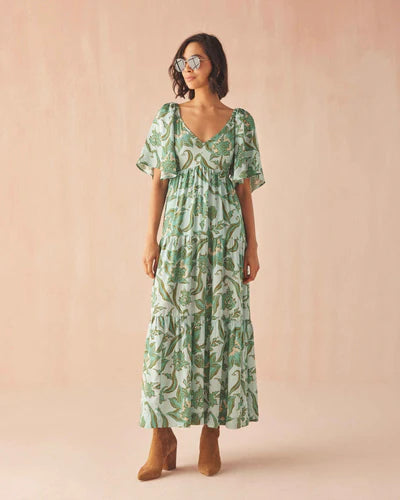 Woman wearing a green patterned dress against a pink background