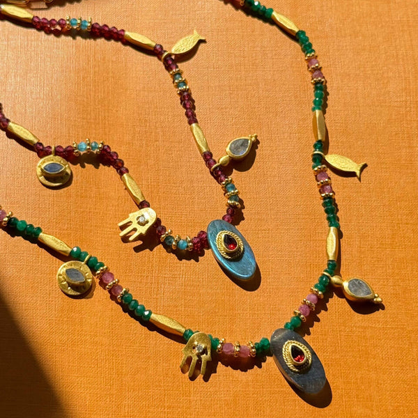 Decorative necklaces with colorful beads and gold accents on an orange background