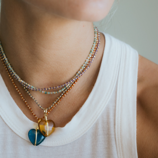 Close-up of a person wearing a colorful beaded necklace with heart-shaped pendants.