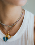 Close-up of a person wearing a colorful beaded necklace with heart-shaped pendants.