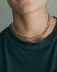 Person wearing a stack of beaded necklaces on a plain background