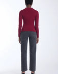 A model shown from the back wearing a fitted burgundy long-sleeve top, dark gray straight-leg jeans, and black high-heeled sandals against a plain white studio background.