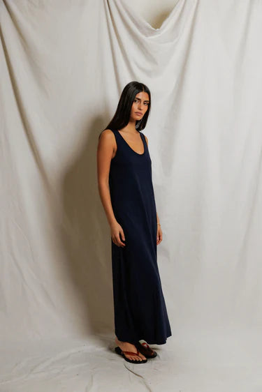 Woman wearing a long navy dress against a plain white background