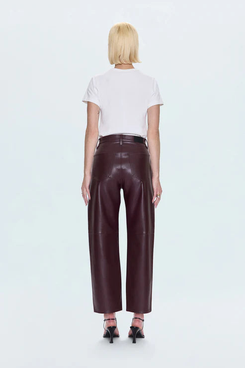 Person wearing a white t-shirt and brown leather pants on a light blue background back view