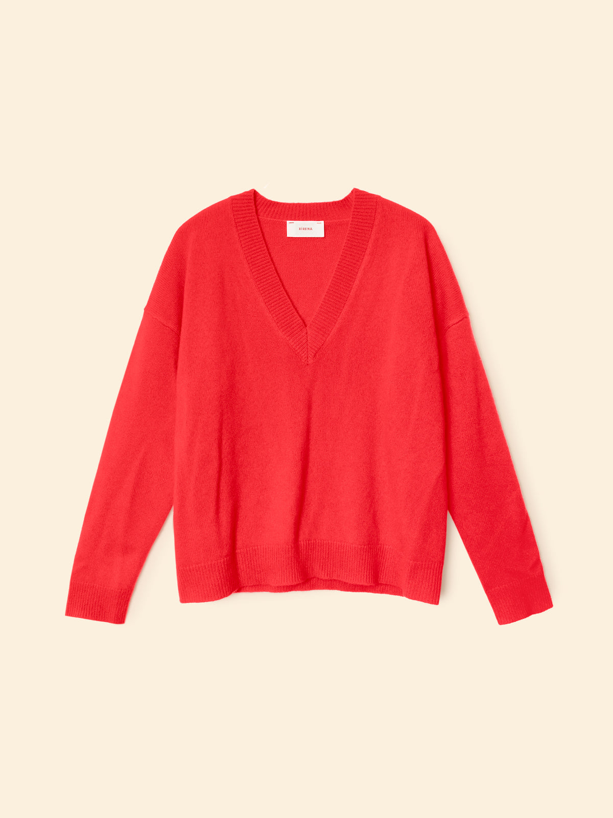 A bright red long-sleeve V-neck knit sweater displayed flat against a solid cream-colored background.