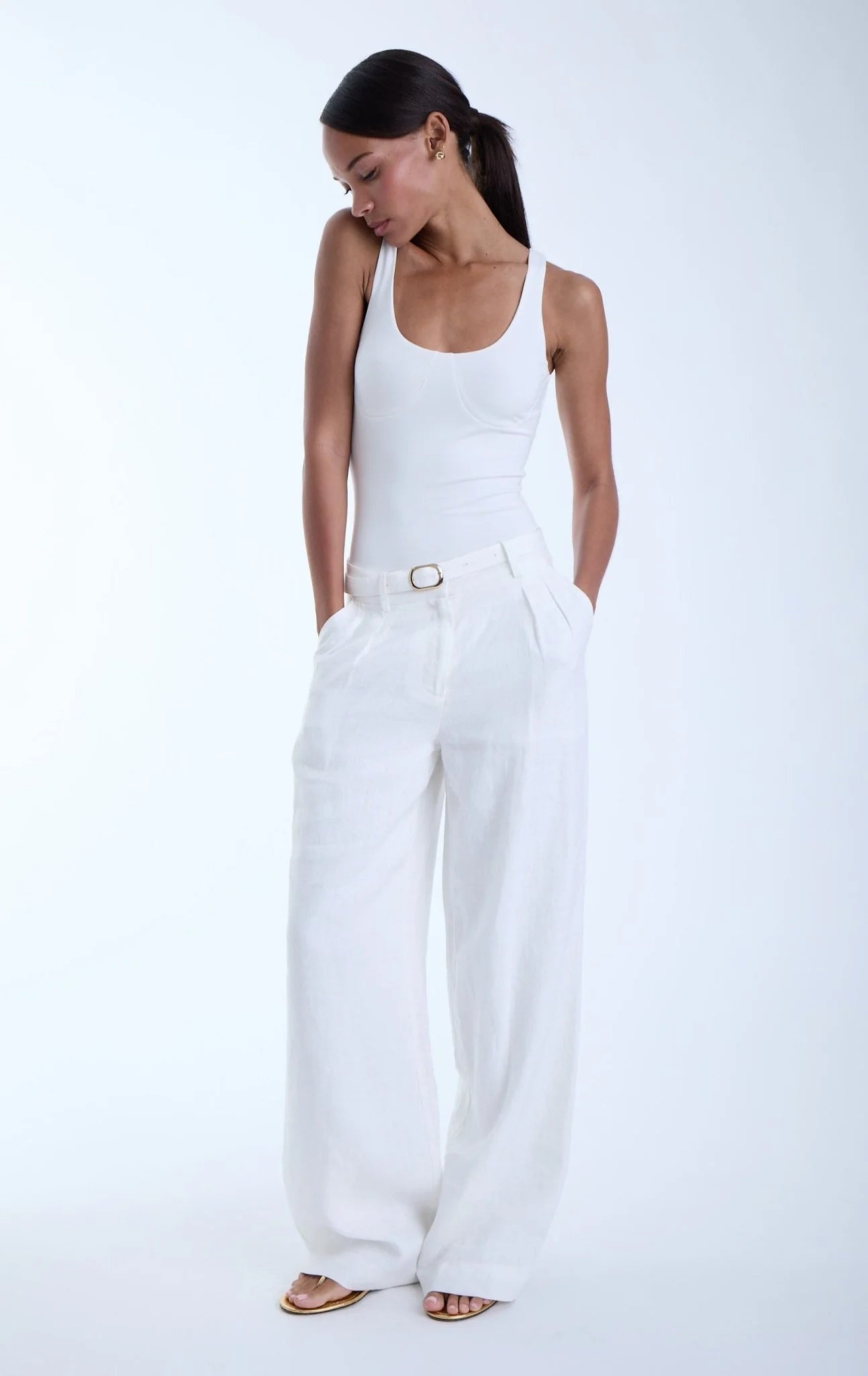 Woman wearing a white sleeveless top and wide-leg pants on a white background
