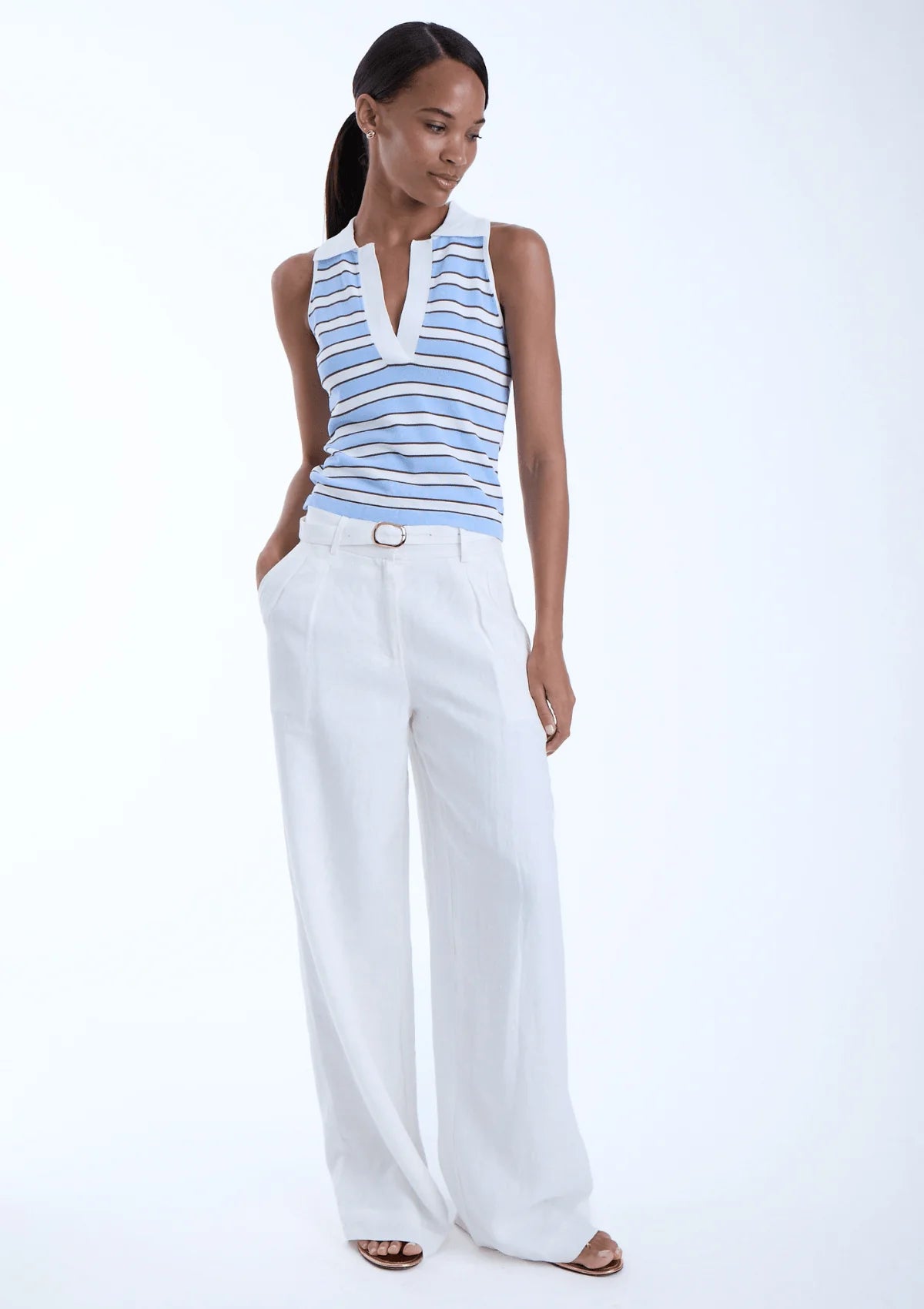model wearing Kira sky sleeveless stripe top with white pants on a white background
