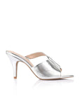 A single metallic silver mule sandal with a pointed toe, crisscrossing front straps, and a slim high heel, shown from a side profile on a white background.