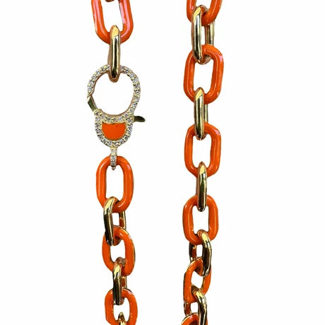 An orange and gold chain necklace featuring elongated links with polished gold-toned edges and a decorative clasp adorned with small clear stones and an orange accent, shown against a plain white background.
