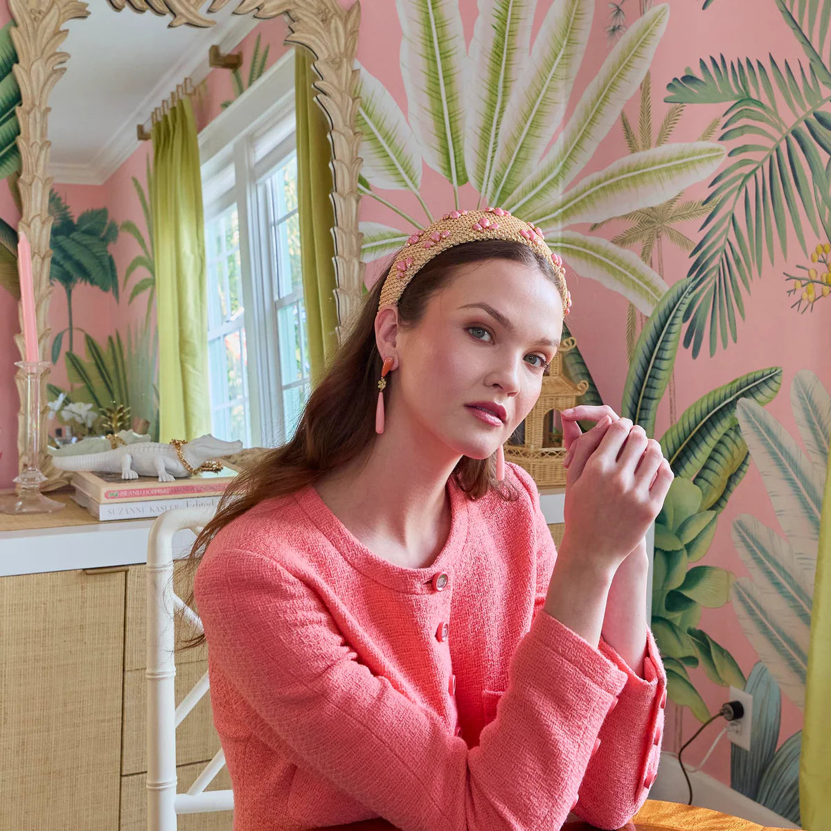 Woman in a pink room with tropical wallpaper and decor