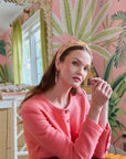 Woman in a pink room with tropical wallpaper and decor