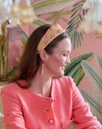 Woman wearing a pink jacket and headband with a tropical-themed background