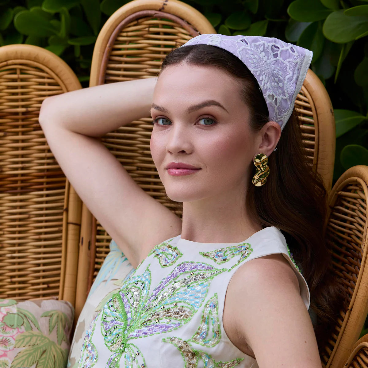 Woman sitting on a wicker chair wearing a decorative headscarf and dress 