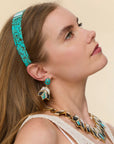 model wearing ONYX TURQUOISE STONE LOTUS EARRINGS with a matching necklace on a cream background