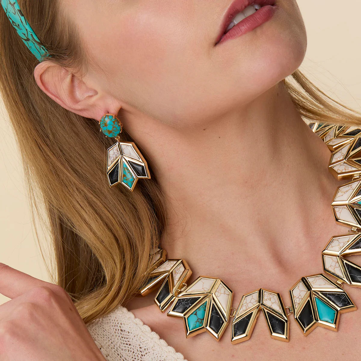 model wearing ONYX TURQUOISE STONE LOTUS EARRINGS with a matching necklace on a cream background