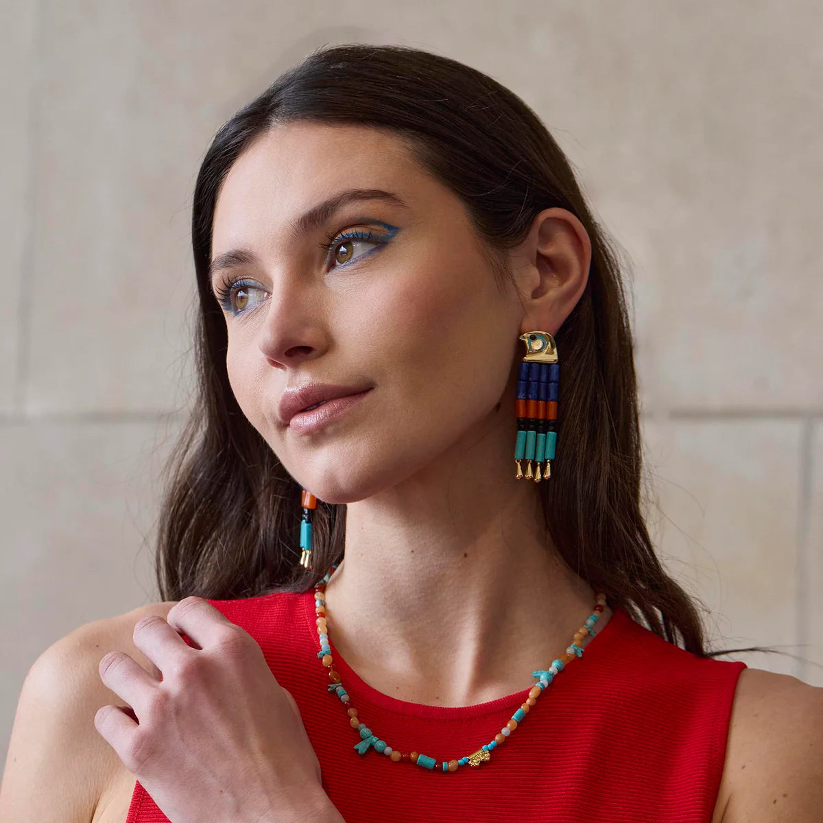 model wearing colorful earrings and necklace on a beige background