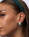 Close-up of a woman's face wearing turquoise earrings and headband.
