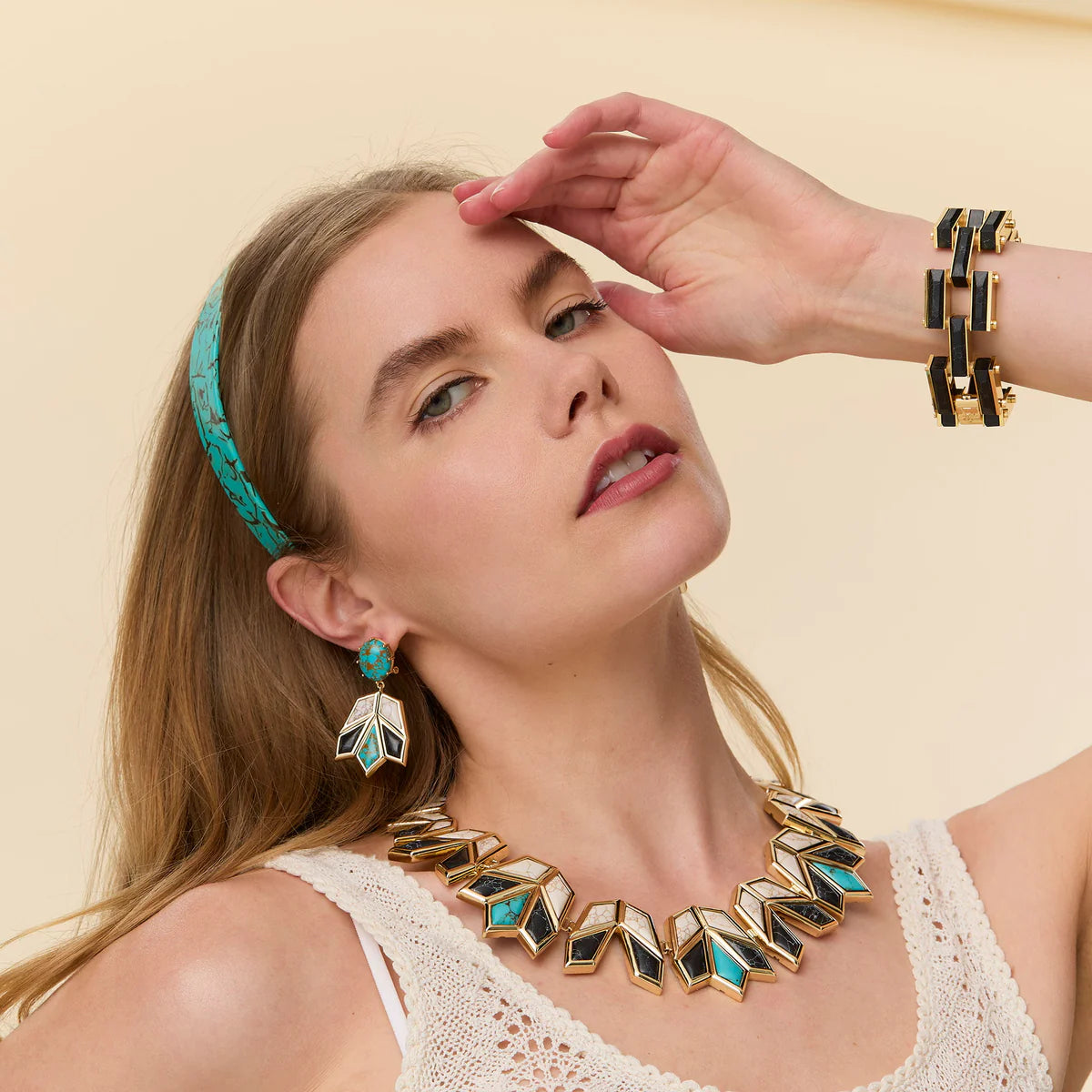 model wearing onyx and turquoise necklace and earrings on a cream background