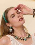 model wearing onyx and turquoise necklace and earrings on a cream background