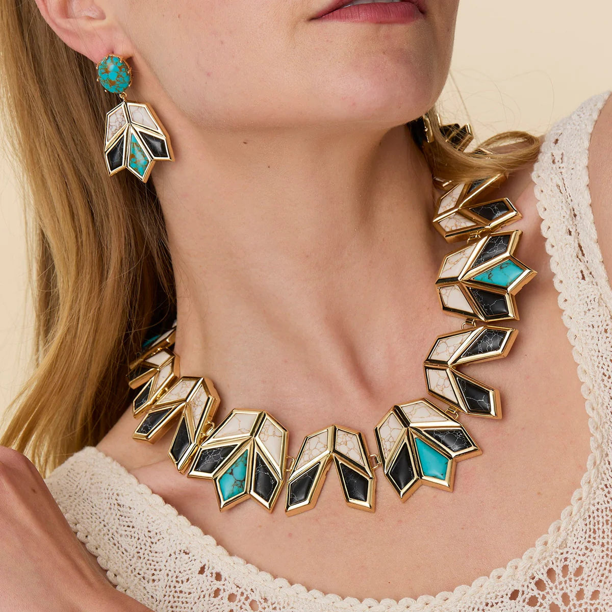 model wearing onyx and turquoise necklace and earrings on a cream background